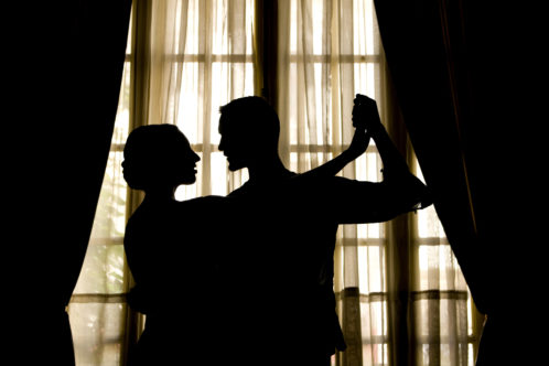 A couple dance in silhouette in front of french doors for an evening entertainment event at mercure hotels