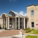 Exterior shot of Mercure York Fairfield Manor Hotel, driveway, columns, potted plants
