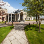 Exterior shot of Mercure York Fairfield Manor Hotel, driveway, columns, potted plants