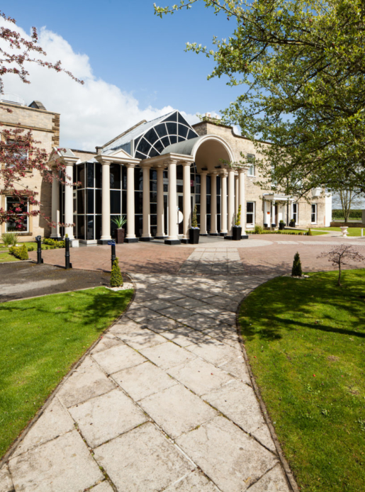 Exterior shot of Mercure York Fairfield Manor Hotel, driveway, columns, potted plants