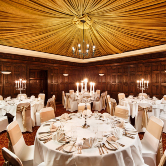 The Oak Room at Mercure York Fairfield Manor Hotel, original oak panelling and draped tented ceiling, chandelier, set up for a wedding breakfast
