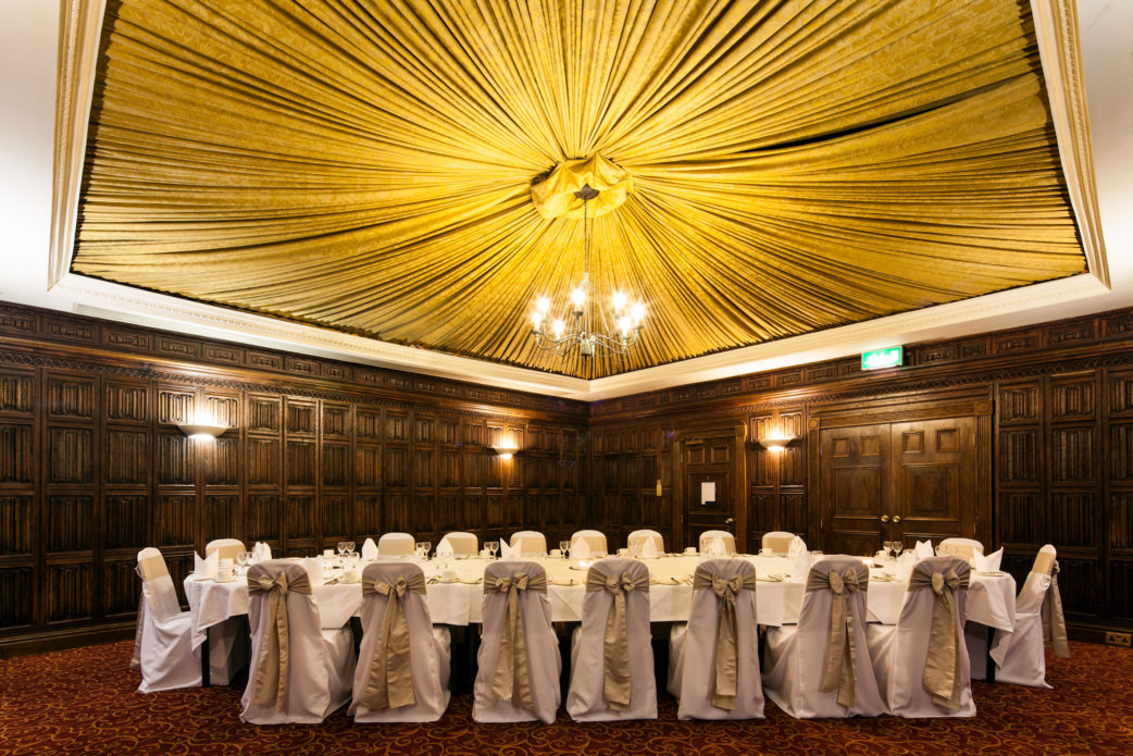 The Oak Room at Mercure York Fairfield Manor Hotel, original oak panelling and draped tented ceiling, chandelier, set up for a wedding breakfast