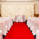 The Park Lane Suite at Mercure York Fairfield Manor Hotel, set up for a wedding ceremony, red carpet aisle, white fairy lights