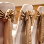 Close up of gold ribbons on white chair covers