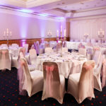 The Parkside Suite at Mercure York Fairfield Manor Hotel, set up for a wedding breakfast, purple lighting, white and pink linen, silver candlesticks