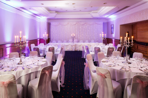 The Parkside Suite at Mercure York Fairfield Manor Hotel, set up for a wedding breakfast, purple lighting, white and pink linen, silver candlesticks