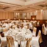 The Parkside Suite at Mercure York Fairfield Manor Hotel, set up for a wedding breakfast, white linen, gold ribbons, silver candlesticks