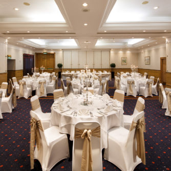 The Parkside Suite at Mercure York Fairfield Manor Hotel, set up for a wedding breakfast, white linen, gold ribbons, silver candlesticks