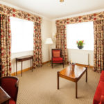 Superior bedroom at Mercure York Fairfield Manor Hotel, separate lounge area, sofa, armchair, tv, champagne on table