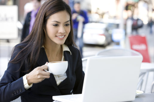 Businesswoman Using Laptop at Outdoor Cafe Drinking Coffee, Copyspace